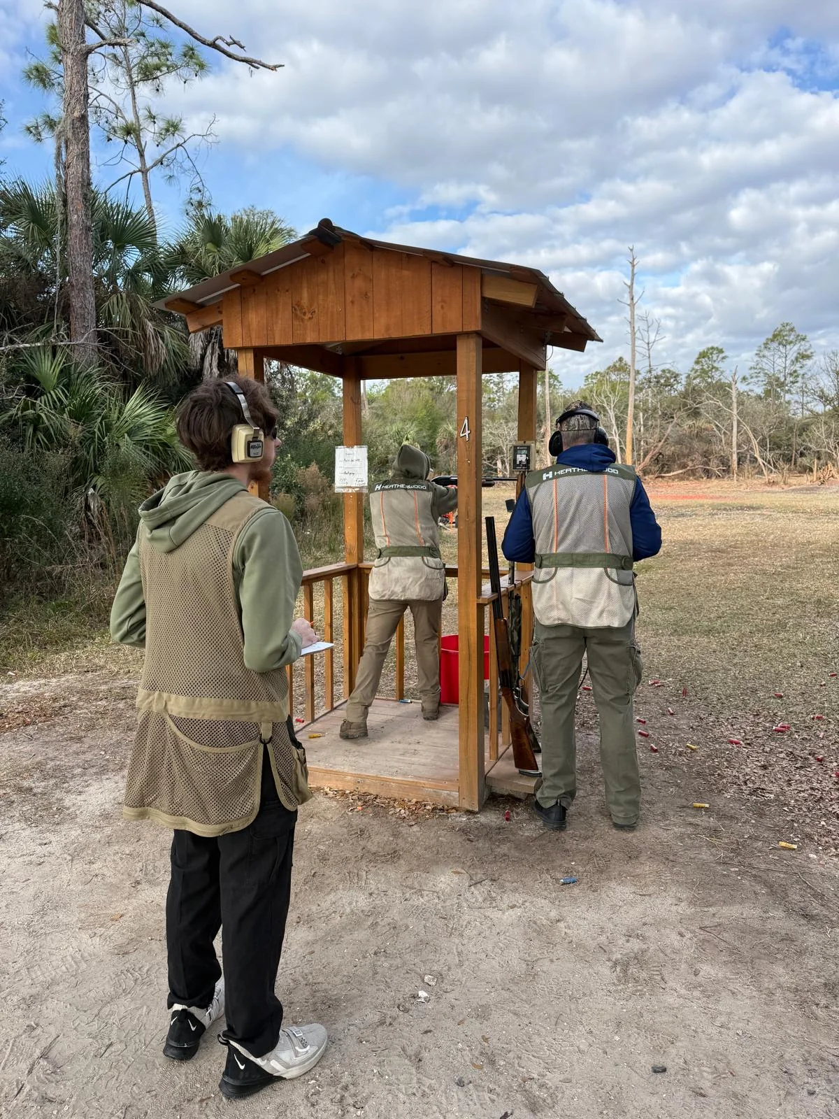 Participants wearing hearing protection at an outdoor shooting station during the 3rd Annual Bravo Shotgun Blast