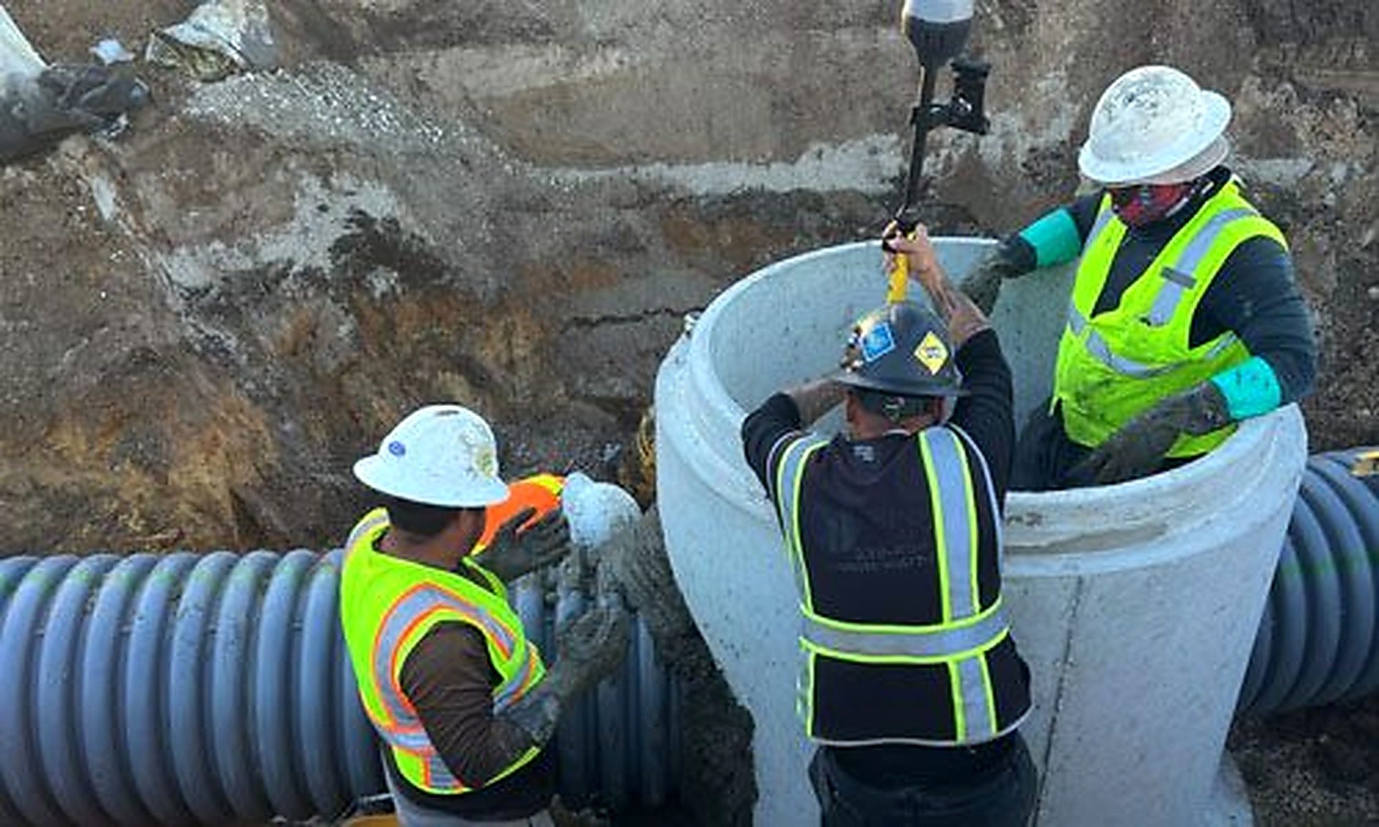 Wet-utility crew working around a precast drainage structure